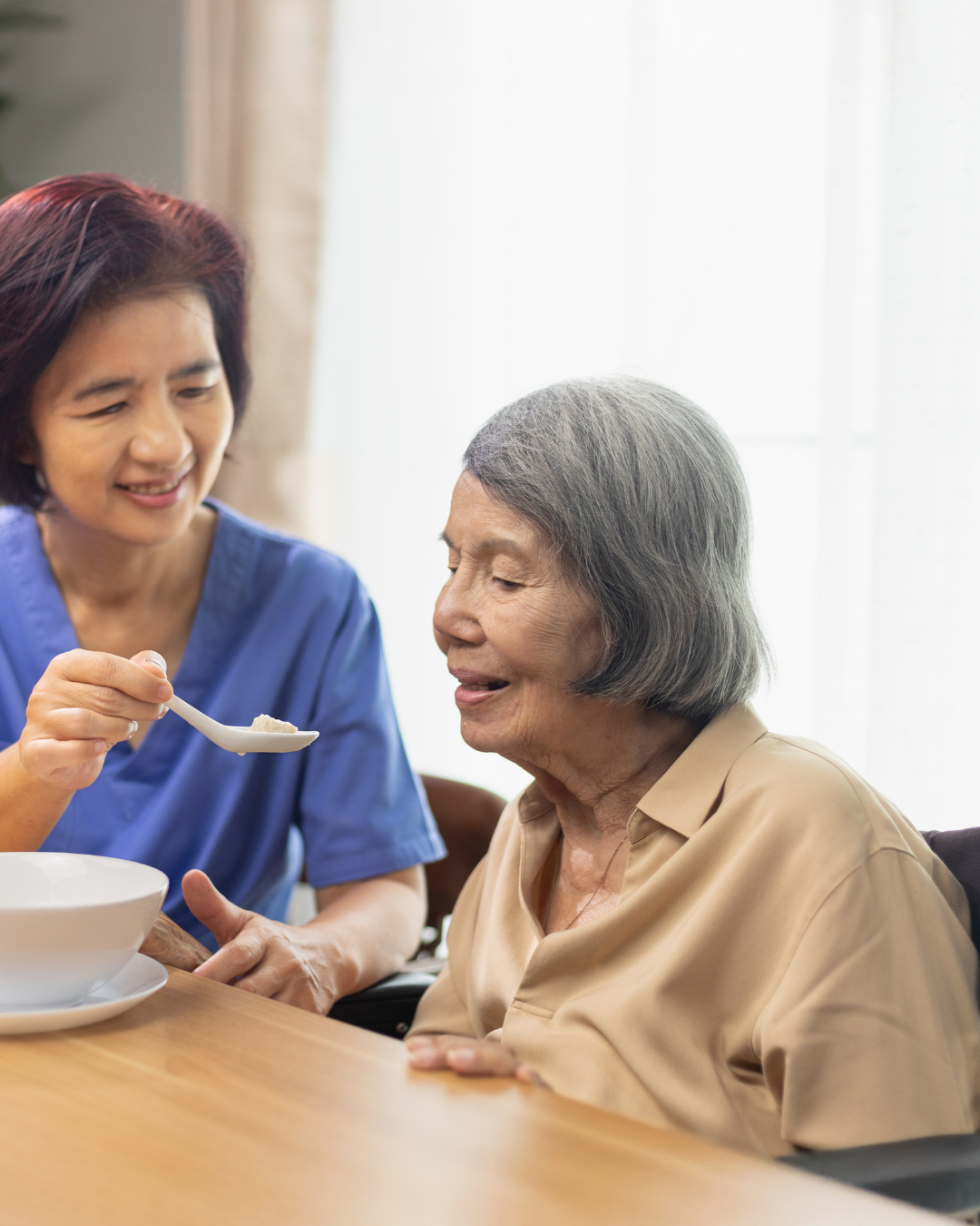 Caregiver providing standby fall prevention assistance to senior using cane while walking outdoors in Los Angeles home garden.